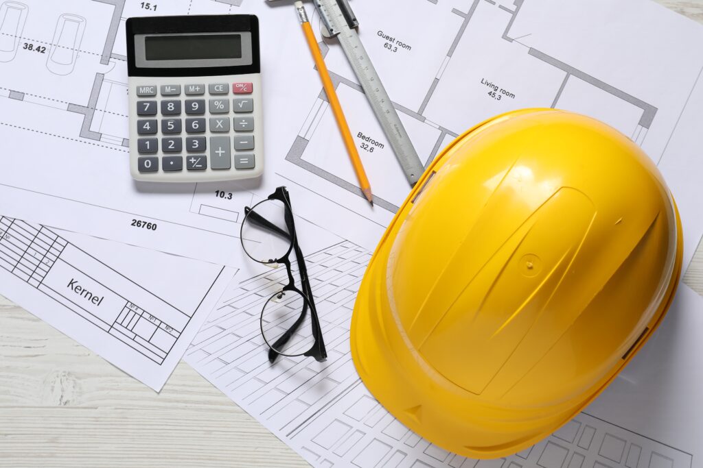 Different architectural drawings hard hat pencil vernier caliper calculator and glasses on light wooden table flat lay